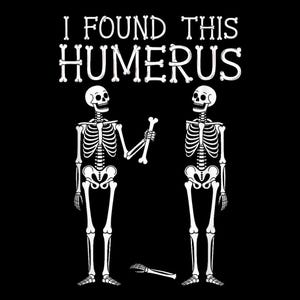 May include: Black graphic with the text "I FOUND THIS HUMERUS" in a bone-like font. Two white skeleton figures stand facing each other, one holding a bone. A detached hand and bone lie on the ground.