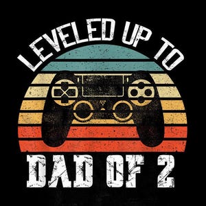 Könnte beinhalten: Eine Grafik im Retro-Stil mit einem Videospiel-Controller und dem Text "LEVELED UP TO DAD OF 2". Die Grafik hat einen Sonnenuntergangs-Hintergrund mit einem Farbschema aus Rot, Orange und Gelb.