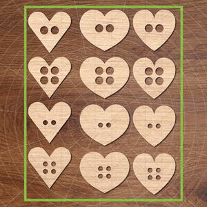May include: Nine wooden heart-shaped buttons with varying hole configurations. The buttons are light brown and arranged in a grid pattern. The image is set against a wooden background.