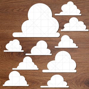 May include: A collection of white cloud cutouts in various sizes arranged on a brown wooden surface. The clouds have a simple, cartoon-like design with a grid pattern. The image includes the text "Doodles Doodles Studio" in a green box.