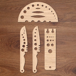 Könnte beinhalten: Holzwerkzeug-Set auf einer Holzmaserungsoberfläche. Das Set enthält zwei messerförmige Werkzeuge, ein rechteckiges Werkzeug mit Löchern und ein halbkreisförmiges Werkzeug mit unterschiedlich großen Löchern. Die Werkzeuge sind hellbraun.
