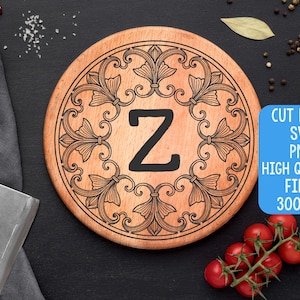 Könnte beinhalten: Ein rundes Holzschneidebrett mit einem dekorativen floralen Rand und dem Buchstaben "Z" in der Mitte. Das Brett ist hellbraun mit dunkelbraunen Gravurdetails. Das Bild enthält auch den Text "CUT FILES SVG PNG HIGH QUALITY FILES 300 DPI".