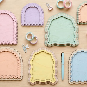 Peut inclure: Un ensemble de six plaques en bois en forme d'arche avec des bords festonn&eacute;s dans des tons pastel incluant rose, lavande, vert, p&ecirc;che, jaune et bleu, dispos&eacute;es avec de la papeterie comme du ruban adh&eacute;sif, des trombones et un stylo.