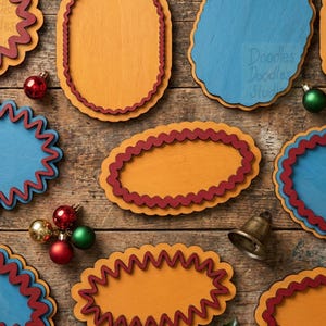 Peut inclure: Une collection de plaques ovales en bois aux bords festonn&eacute;s jaune moutarde et bleu, rehauss&eacute;es de bordures ondul&eacute;es rouge fonc&eacute;. De petites boules d&eacute;coratives rouges, vertes et dor&eacute;es ainsi qu'une cloche en m&eacute;tal sont &eacute;parpill&eacute;es parmi les formes.