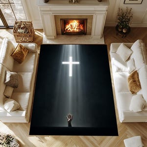 Könnte beinhalten: Ein großer, rechteckiger Teppich mit einem hellweißen Kreuz, das von einem Lichtstrahl auf dunklem Hintergrund beleuchtet wird. Eine Hand greift von unten nach oben. Der Teppich befindet sich in einem Wohnzimmer.