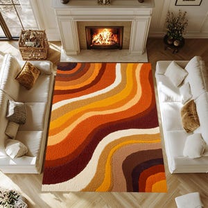 May include: A large, rectangular rug with a retro design. The rug features a wavy pattern of warm colours, including shades of orange, brown, and cream. The rug is placed in a living room setting with white sofas and a fireplace.