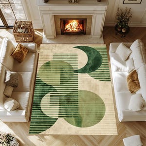 Può includere: Un tappeto rettangolare con un design geometrico nei toni del verde e beige. Il tappeto presenta cerchi, mezzelune e strisce orizzontali. Il tappeto è posto in un soggiorno con divani bianchi, un camino e pavimenti in legno.
