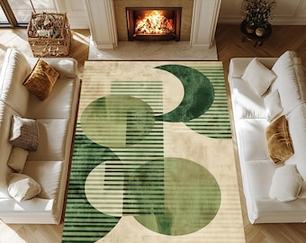 May include: A rectangular area rug with a geometric design in shades of green and beige. The rug features circles, half-moons, and horizontal stripes. The rug is placed in a living room with white sofas, a fireplace, and hardwood floors.