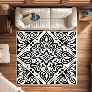 Può includere: Vista dall'alto di un grande tappeto rettangolare con un motivo floreale in bianco e nero. Il tappeto presenta un design simmetrico con foglie stilizzate e forme geometriche. È posato su un pavimento in legno, con un divano bianco sullo sfondo.