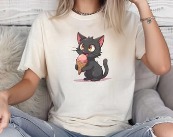 May include: Cream-colored t-shirt featuring a cartoon black cat holding a pink ice cream cone. The cat has yellow eyes and a happy expression. The shirt is made of a soft material and has short sleeves.