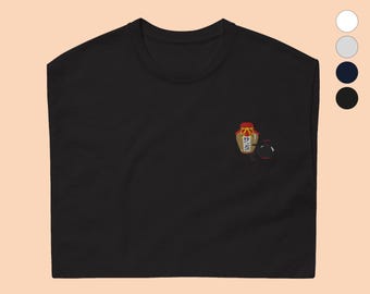 May include: Black t-shirt with a small embroidered image of a jar with a red lid and a black and white image of a cat.