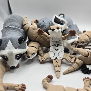 Puede incluir: Una colección de pequeñas figuras de animales articuladas. Las figuras están hechas de plástico marrón claro y presentan detalles realistas. Los animales incluyen un mapache, una nutria y algunos otros mamíferos pequeños.