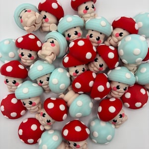 Puede incluir: Una colección de figuras caprichosas con forma de hongo. Las setas tienen sombreros rojos con lunares blancos y sombreros azul claro con lunares blancos. Cada figura tiene una cara sonriente y un cuerpo beige.