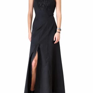 Könnte beinhalten: Schwarzes Neckholder-Kleid mit hohem Schlitz. Das Oberteil hat aufwendige Perlenarbeiten, der Rock einen Spitzensaum. Das Kleid ist bodenlang und für formelle Anlässe geeignet.