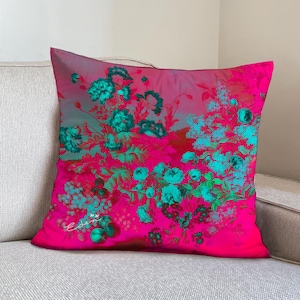 Könnte beinhalten: Ein rosa-türkisfarbenes Blumenkissen mit dem Wort "Eden" in weißer Schrift.