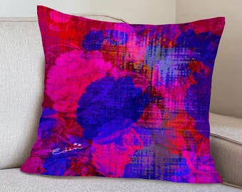 Op de afbeelding: Een roze en blauwe bloemen kussen met een verweerd, abstract ontwerp. Het kussen heeft de tekst "Eden" erop gedrukt.