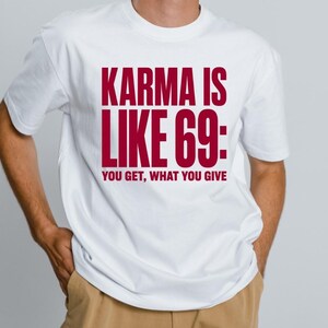 May include: A white short-sleeved t-shirt featuring bold dark red text on the chest that reads: KARMA IS LIKE 69: YOU GET, WHAT YOU GIVE. The garment has a classic crew neckline and a standard fit, showcasing the printed message clearly on the front.