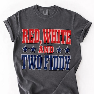 May include: A charcoal grey short-sleeve t-shirt featuring the text RED, WHITE AND TWO FIDDY in red, white, and blue block lettering. The design includes four navy blue stars flanking the word AND, centered on the front of the garment.