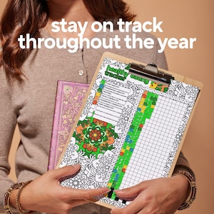 May include: A wooden clipboard with a "healthy eating tracker" chart, featuring a colorful mandala design and a grid for tracking. The text "stay on track throughout the year" is at the top. A decorative journal is held in the background.
