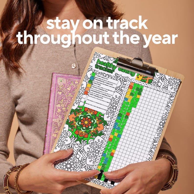 May include: A wooden clipboard with a "healthy eating tracker" chart, featuring a colorful mandala design and a grid for tracking. The text "stay on track throughout the year" is at the top. A decorative journal is held in the background.