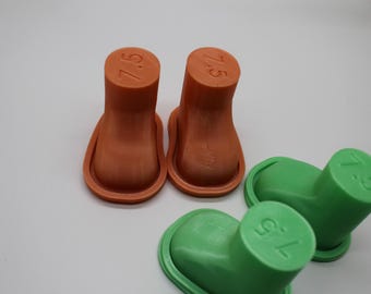 May include: Two orange and two green boot-shaped plastic molds, each featuring the number 7.5 embossed on the top surface. These items have a smooth, solid construction with a raised rim around the base, designed for crafting or molding purposes.