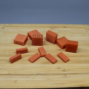 May include: A collection of small, orange-red brick-shaped objects on a wooden cutting board. The bricks are made of a textured material and have a variety of sizes and shapes.