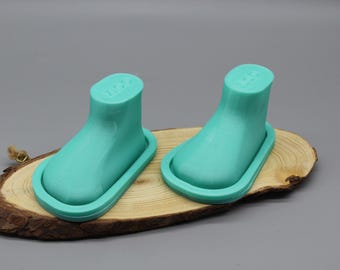 May include: A pair of mint green silicone boot-shaped molds with a smooth finish. Each mold features a raised rim around the base and the embossed text "ZICO" on the top surface of the ankle section, designed for crafting or casting purposes.