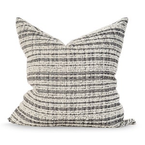 May include: A white and black striped throw pillow with a textured fabric.