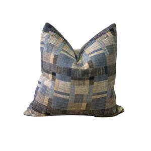 May include: A blue, brown, and beige patterned throw pillow with a square geometric design.