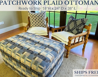 May include: Patchwork plaid ottoman with a blue, gray, and beige geometric pattern. The ottoman is 18 inches high, 24 inches deep, and 38 inches long. Two wooden chairs with patterned pillows and white cushions are in the background.