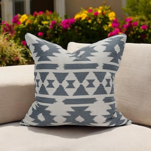 May include: A white and blue geometric patterned throw pillow with a white background and a dark blue geometric pattern.