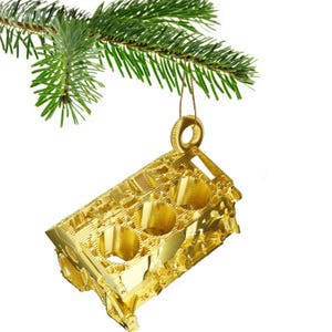 Peut inclure: Ornement de Noël doré en forme de bloc moteur, suspendu à une branche de pin verte. L'ornement présente des détails complexes et une finition brillante. Il est suspendu par une ficelle dorée, parfait pour les passionnés d'automobile.