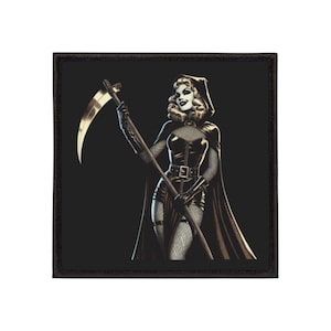 Op de afbeelding: Vierkante patch met een zwart-wit illustratie van een vrouw in een capuchonmantel die een zeis vasthoudt. De vrouw draagt een korset, visnetkousen en handschoenen. De patch heeft een zwarte rand.