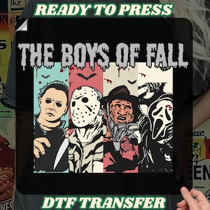May include: Black t-shirt with a graphic design of horror movie characters, including Michael Myers, Jason Voorhees, Freddy Krueger, and Ghostface, with the text "THE BOYS OF FALL". The words "READY TO PRESS" and "DTF TRANSFER" are also visible.