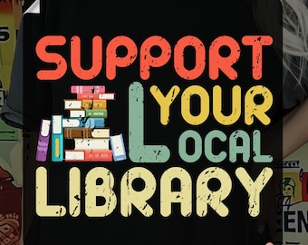 May include: Black t-shirt with the text "SUPPORT YOUR LOCAL LIBRARY" in orange, yellow, and blue. The design includes a stack of colorful books. The words "READY TO PRESS" and "DTF TRANSFER" are also visible.