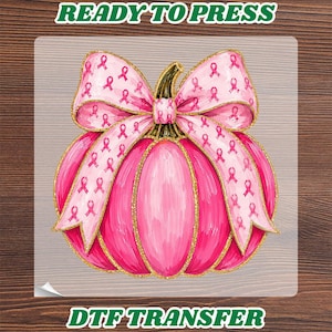 May include: A DTF transfer featuring a bright pink pumpkin with gold glitter outlines, topped with a large light pink bow patterned with small pink breast cancer awareness ribbons. The text READY TO PRESS and DTF TRANSFER appears in green.
