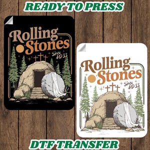 May include: Two DTF transfer designs featuring the text "Rolling Stones Since AD 33" with a tomb illustration. One design is on a black background, the other on white. The words "Ready to Press" and "DTF Transfer" are also present.