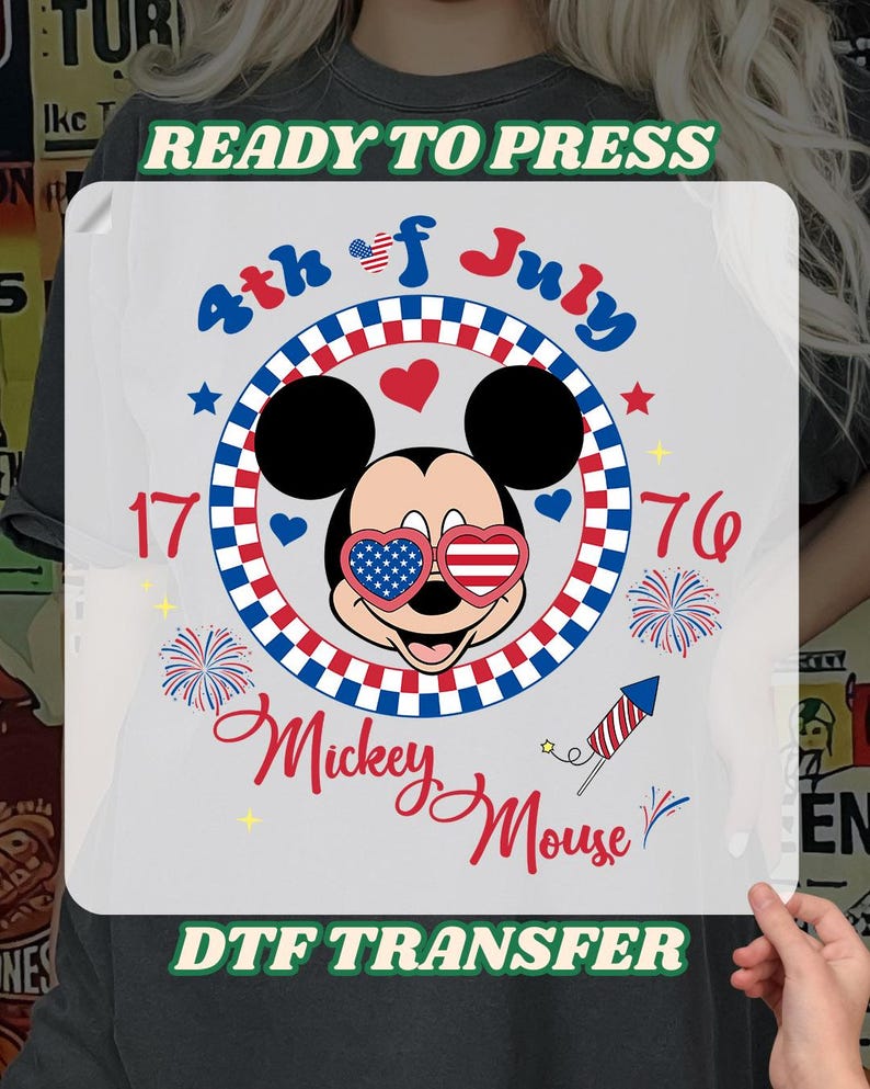 May include: A DTF transfer featuring Mickey Mouse wearing patriotic sunglasses, surrounded by red, white, and blue accents. The design includes the text "4th of July," "1776," and "Mickey Mouse," with fireworks and a rocket.