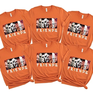 May include: Six orange t-shirts with a graphic featuring horror movie characters and the word "FRIENDS" in white. The graphic includes images of various masked figures and faces from horror films.