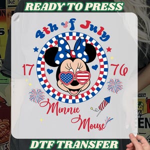 May include: A DTF transfer featuring Minnie Mouse in patriotic colors. Minnie wears heart-shaped sunglasses with a flag design and a polka dot bow. The design includes the text "4th of July" and "1776."