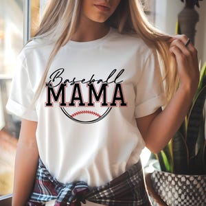 May include: White t-shirt with the text "Baseball MAMA" in black and red, with a baseball graphic. The shirt has short sleeves and a crew neck. The design is centered on the front of the shirt.
