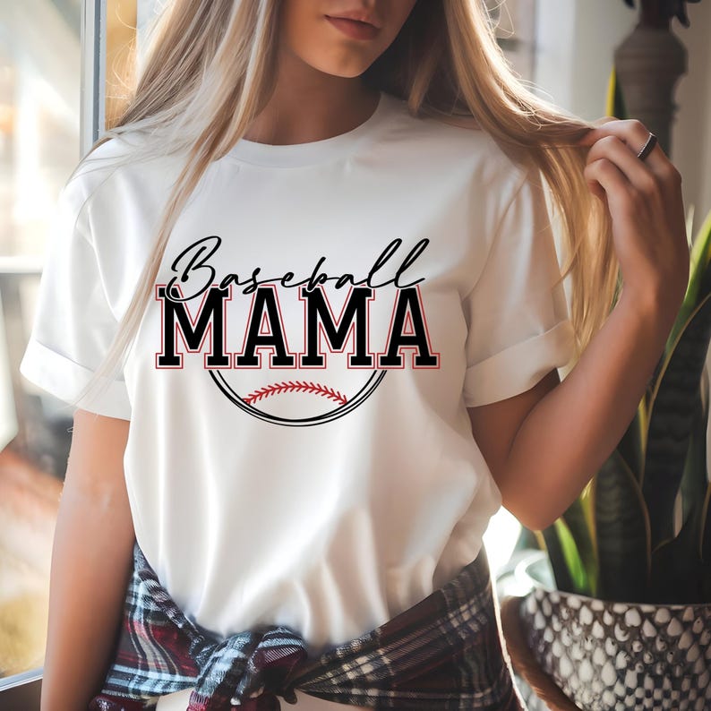 May include: White t-shirt with the text "Baseball MAMA" in black and red, with a baseball graphic. The shirt has short sleeves and a crew neck. The design is centered on the front of the shirt.