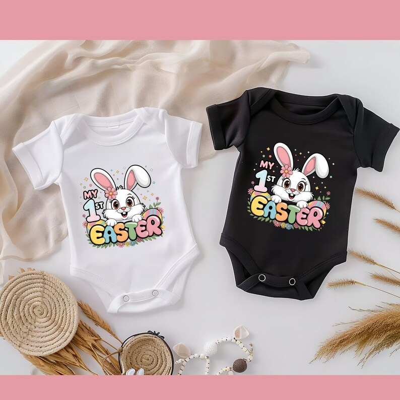 May include: Two white and black baby onesies with short sleeves. The onesies feature a cartoon bunny rabbit with the text "My 1st Easter" in colorful letters.