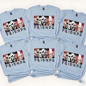 May include: Light blue t-shirts with a graphic featuring horror movie characters and the word "FRIENDS" in a colorful font. The shirts are short-sleeved and have a crew neck design. The image shows six shirts.