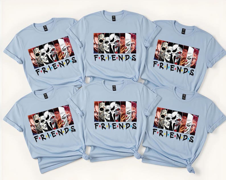May include: Light blue t-shirts with a graphic featuring horror movie characters and the word "FRIENDS" in a colorful font. The shirts are short-sleeved and have a crew neck design. The image shows six shirts.