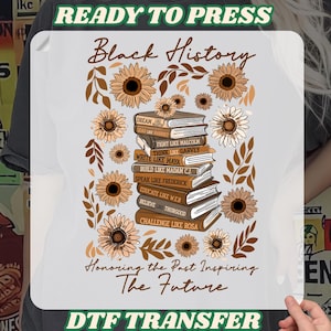 May include: White DTF transfer featuring the text "Black History" in a script font, with a stack of books and sunflowers. The books have inspirational phrases. The phrase "Honoring the Past Inspiring The Future" is also included.