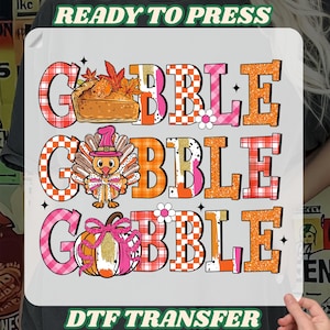 May include: A DTF transfer with the words "GOBBLE GOBBLE GOBBLE" in a layered design. Each word has a different pattern and is accompanied by Thanksgiving-themed graphics, including a pie, turkey, and pumpkin. The text "READY TO PRESS" and "DTF TRANSFER" are also included.