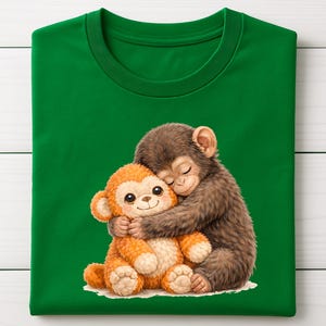 Op de afbeelding: Groen t-shirt met een cartoon illustratie van twee knuffelende apen. E&eacute;n aap is bruin, de andere oranje. De afbeelding toont de apen op een witte achtergrond.
