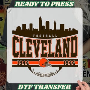 May include: A DTF transfer featuring the city skyline, the word "FOOTBALL", and the name "CLEVELAND" in brown and orange. Includes a football helmet and the year "1944". The text "READY TO PRESS" and "DTF TRANSFER" are also present.