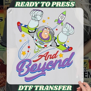May include: A DTF transfer featuring Buzz Lightyear in a flying pose with a rocket, stars, and the words "And Beyond." The design is in bright colours, with the text "READY TO PRESS" and "DTF TRANSFER" at the top and bottom.